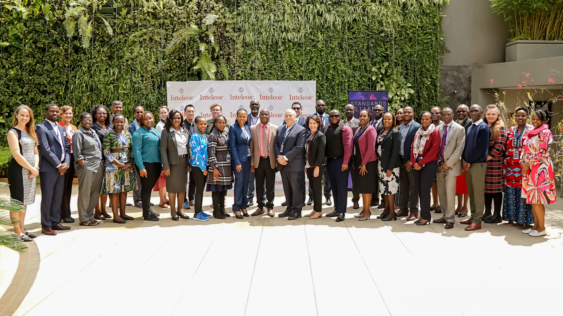a large group of people standing in front of an inteleos step and repeat at a conference in kenya