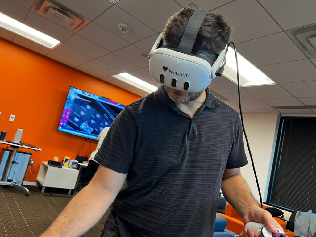 a man in a black polo wearing a vantari VR headset that is covering most of his face